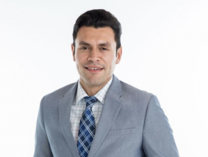 WOOD journalist Ruben Juarez wearing a suit and smiling.